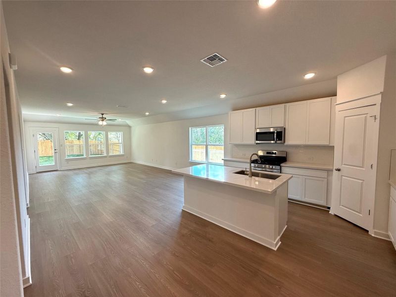 Kitchen with white cabinets, recessed lighting, dark wood-type flooring, a kitchen island with sink, and open floor plan Kitchen with white cabinets, recessed lighting, dark wood-type flooring, a kitchen island with sink, and open floor plan