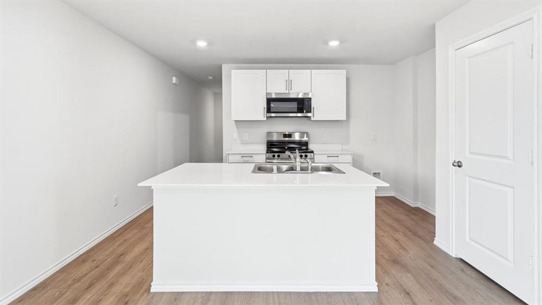 Kitchen with an island with sink, white cabinets, stainless steel appliances, light wood-style flooring, and recessed lighting Kitchen with an island with sink, white cabinets, stainless steel appliances, light wood-style flooring, and recessed lighting