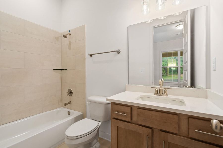 Full bathroom featuring a single vanity with wood-finish cabinetry, a white countertop, and a rectangular undermount sink Full bathroom featuring a single vanity with wood-finish cabinetry, a white countertop, and a rectangular undermount sink