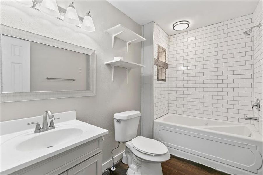 Full bathroom with toilet, hardwood / wood-style floors, tiled shower / bath combo, and vanity Full bathroom with toilet, hardwood / wood-style floors, tiled shower / bath combo, and vanity