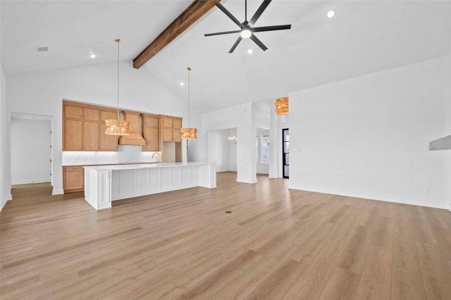 Unfurnished living room featuring high vaulted ceiling, beamed ceiling, a ceiling fan, light wood-type flooring, and recessed lighting Unfurnished living room featuring high vaulted ceiling, beamed ceiling, a ceiling fan, light wood-type flooring, and recessed lighting