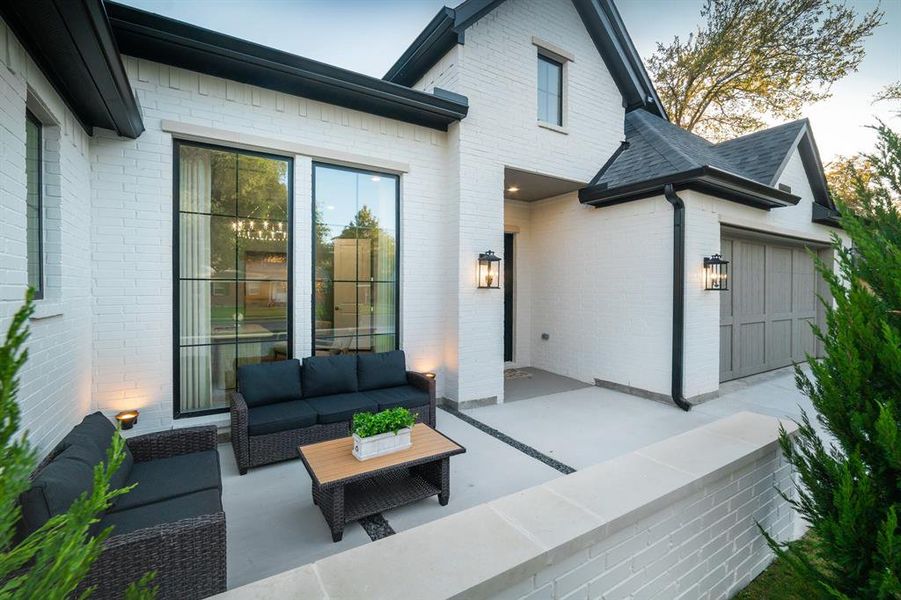 Back of property featuring brick siding, outdoor lounge area, a patio area, and a shingled roof Back of property featuring brick siding, outdoor lounge area, a patio area, and a shingled roof