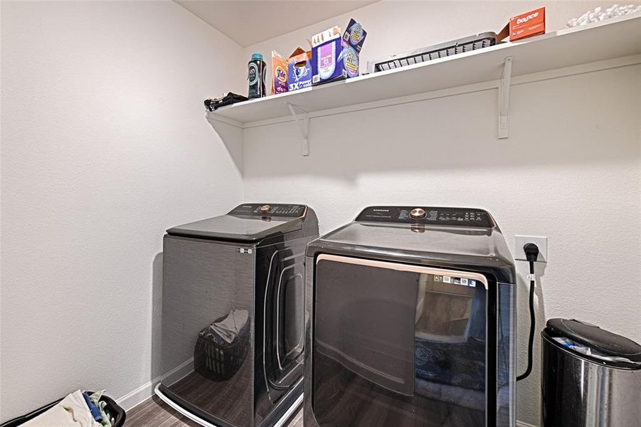 Washroom with washer and dryer, a textured wall, and wood finished floors Washroom with washer and dryer, a textured wall, and wood finished floors
