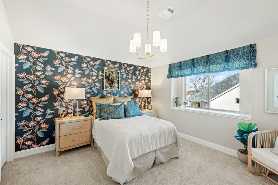 Bedroom with bold floral accent wall, queen bed, chandelier, and carpeted floors Bedroom with bold floral accent wall, queen bed, chandelier, and carpeted floors