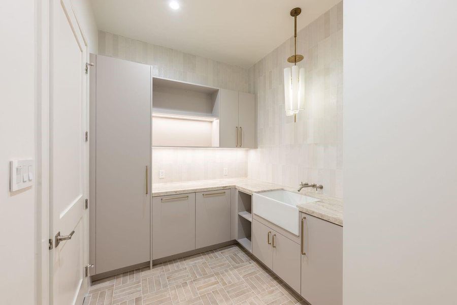 Designed with intention, this elevated laundry corridor pairs clean architectural lines with tactile finishes for a space that feels calm and collected. Custom cabinetry floats above a full hanging station, while sleek front-load appliances tuck seamlessly beneath tailored storage.
