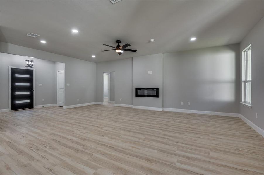 Unfurnished living room with light wood-style floors, a glass covered fireplace, a ceiling fan, and recessed lighting Unfurnished living room with light wood-style floors, a glass covered fireplace, a ceiling fan, and recessed lighting