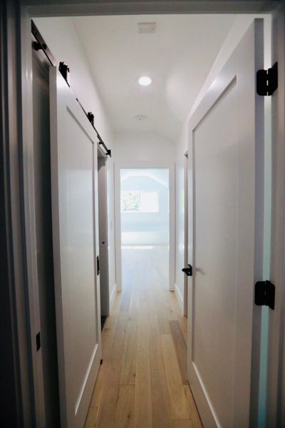 Hallway with a barn door, light wood-style floors, and recessed lighting