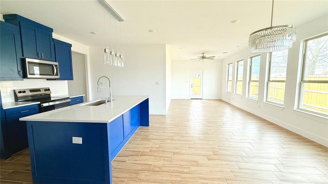 Kitchen with blue cabinetry, stainless steel appliances, light countertops, and a sink