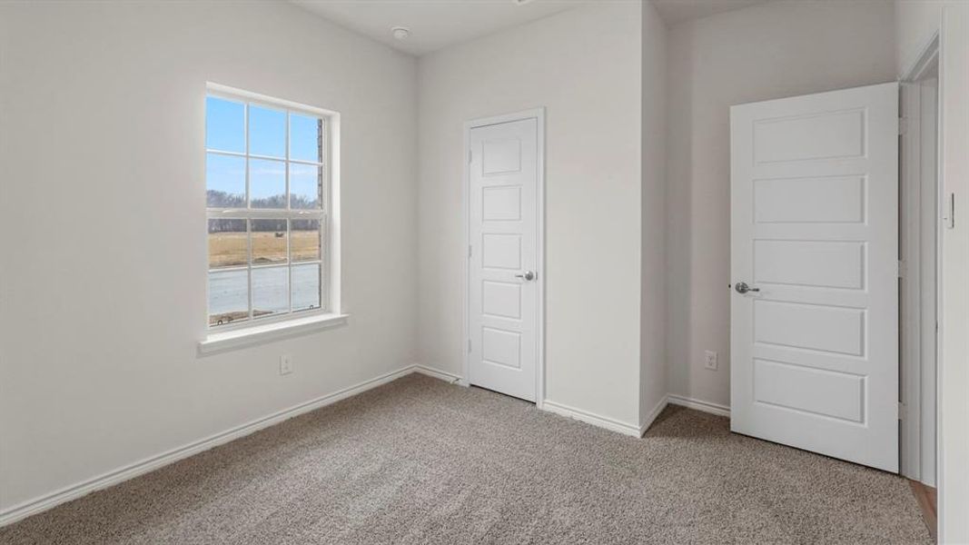 Room featuring a window with grid pattern, neutral carpet flooring, white walls, and two paneled interior doors