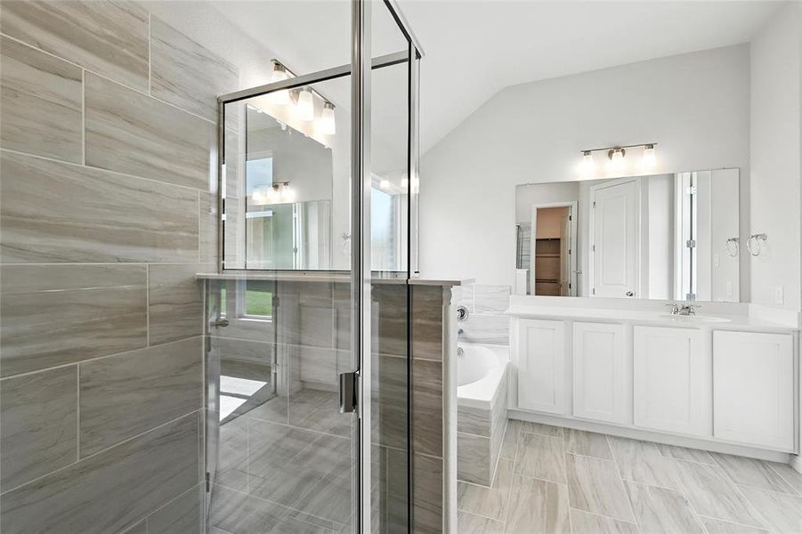 Bathroom with a garden tub, vaulted ceiling, vanity, and a stall shower