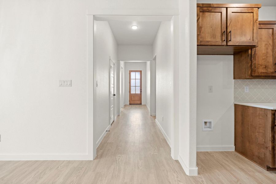 A welcoming entryway with light-toned flooring leads to a kitchen featuring warm wood cabinetry.