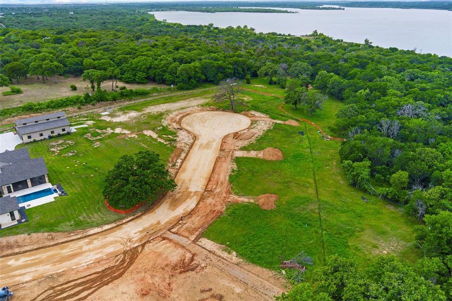 Developing cul-de-sac lot featuring partial clearing, surrounding mature trees, and a distant water body Developing cul-de-sac lot featuring partial clearing, surrounding mature trees, and a distant water body
