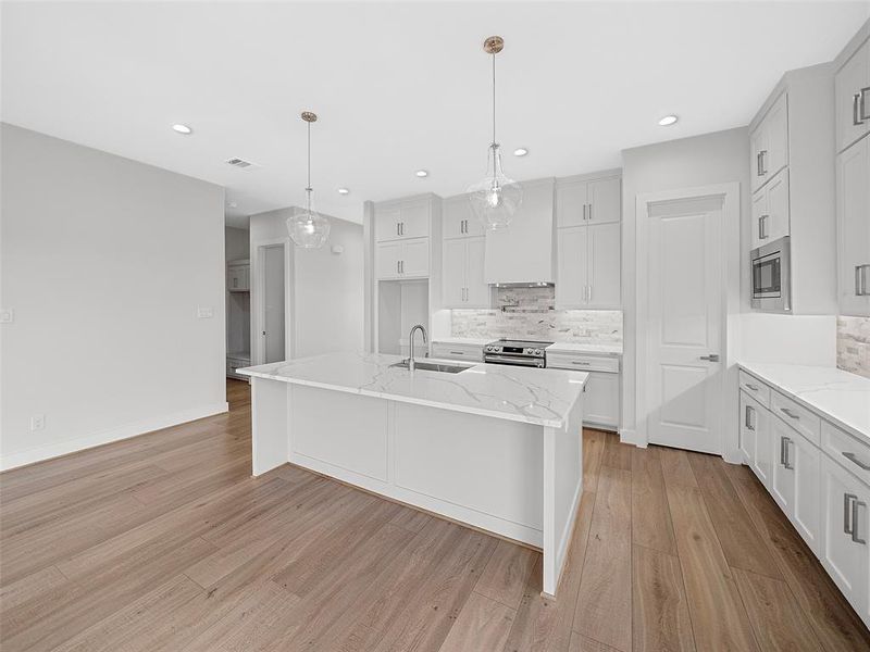 Kitchen with stainless steel appliances, light hardwood / wood-style floors, tasteful backsplash, sink, and white cabinets