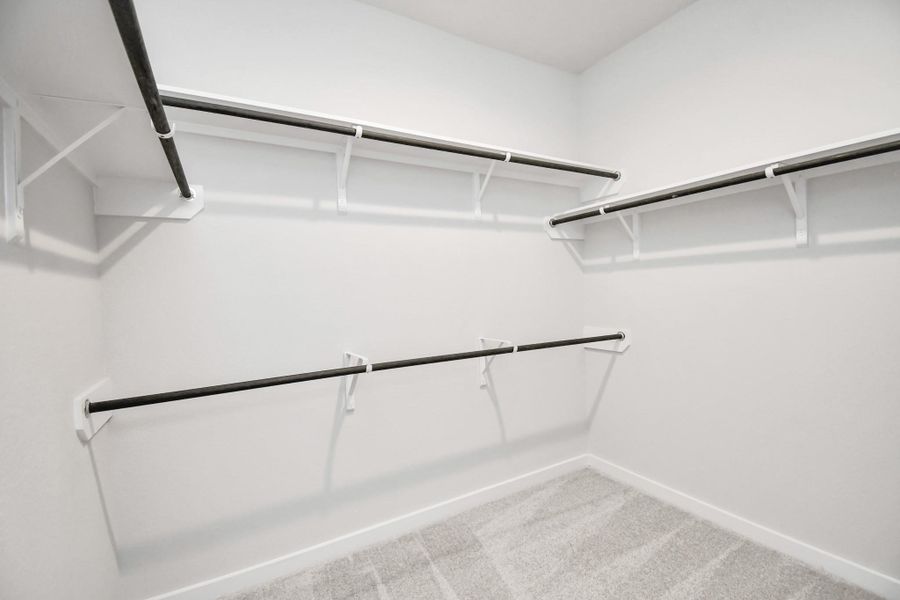 Walk-in closet that epitomizes luxury and practicality. This generously sized space features built-in shelving, offering abundant room for impeccable organization. High ceilings and recessed lighting create a bright and welcoming ambiance. Sample photo of completed home with similar floor plan. Actual colors and selections may vary.