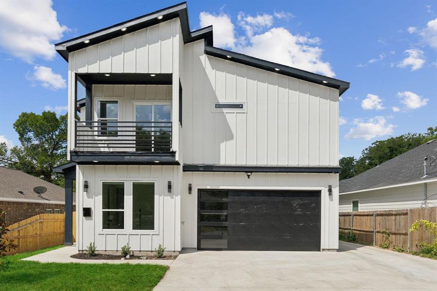 View of front of home featuring a garage and a balcony