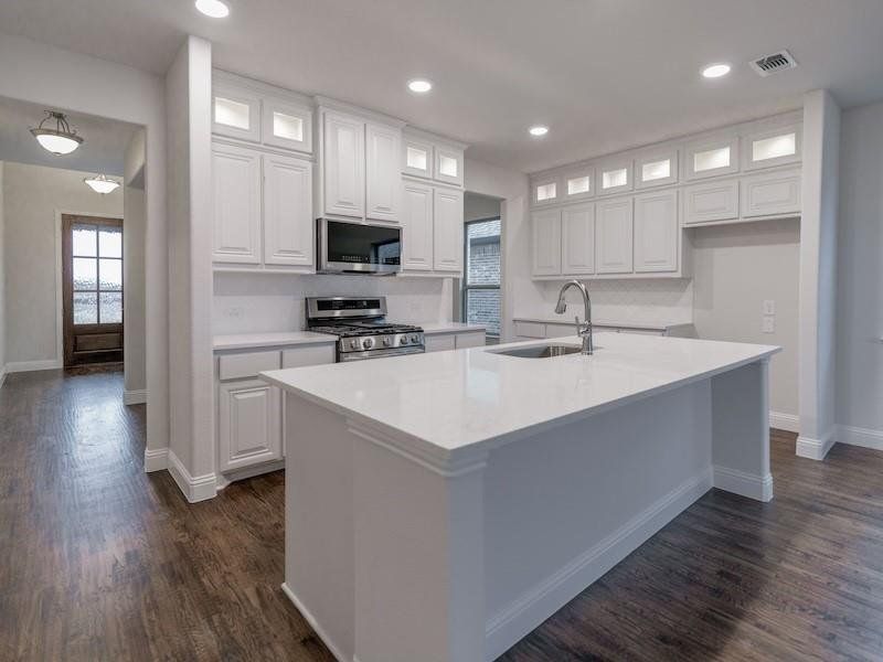 Kitchen featuring an island with sink, appliances with stainless steel finishes, sink, and white cabinets