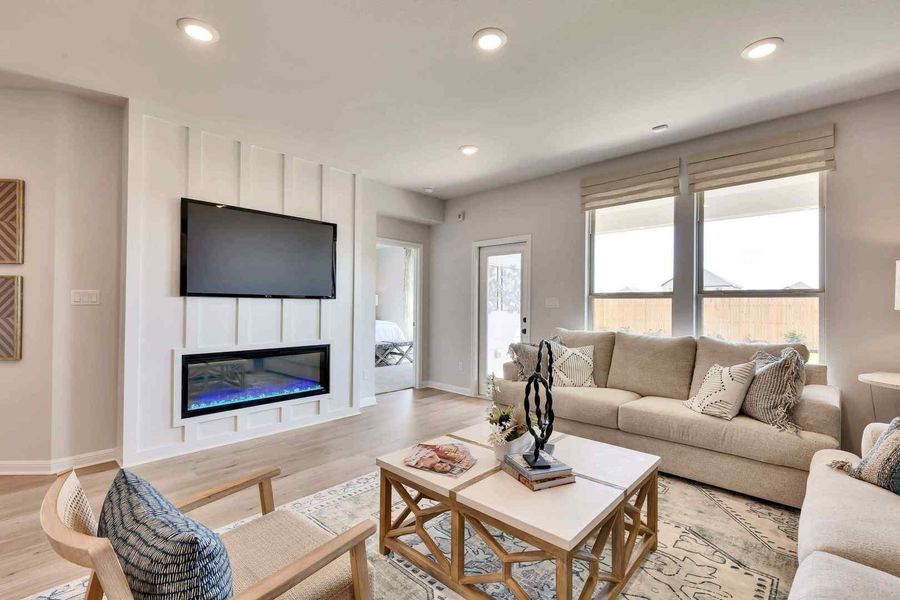 An inviting gathering space features an electric fireplace with a contemporary mantel and recessed lighting, creating a comfortable ambiance.