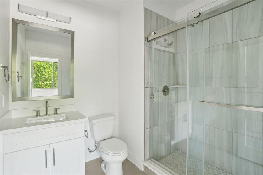 Full bath with toilet, a stall shower, and vanity