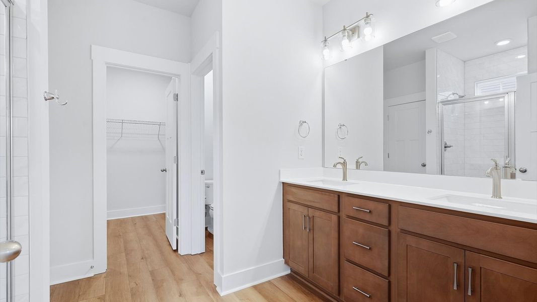 Memorable mornings begin in this elegant primary bathroom with walk-in shower and double vanity by DRB Homes