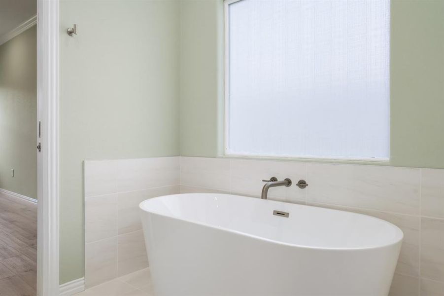 Bathroom featuring tile walls, hardwood / wood-style flooring, and a tub