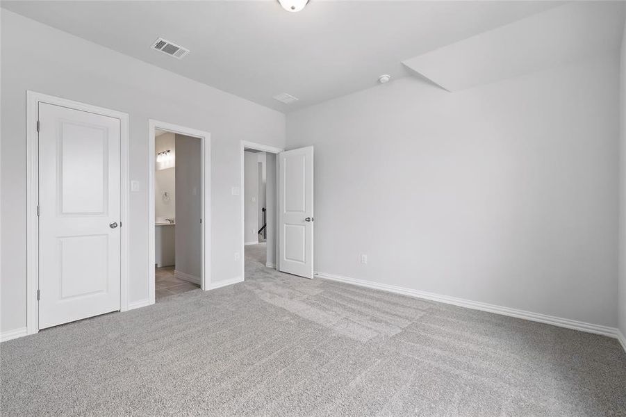 Unfurnished bedroom with light carpet and ensuite bath