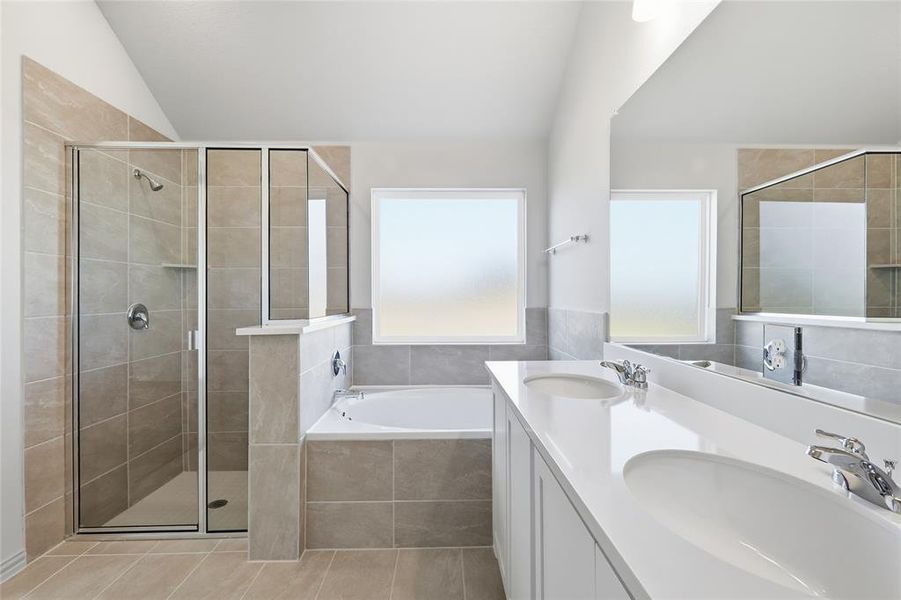 Full bath with double vanity, a bath, lofted ceiling, and a stall shower Full bath with double vanity, a bath, lofted ceiling, and a stall shower