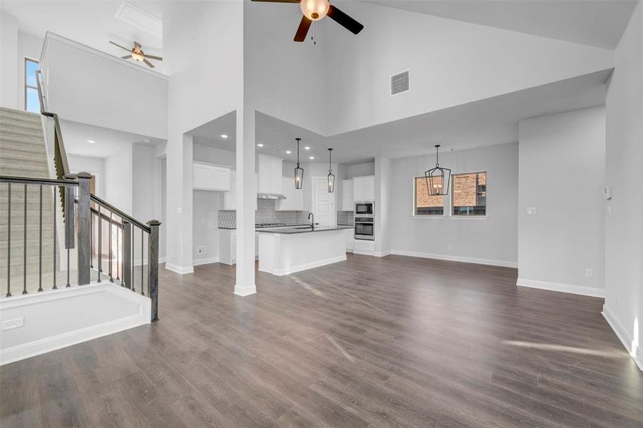 Unfurnished living room featuring ceiling fan, dark wood-style floors, and lofted ceiling Unfurnished living room featuring ceiling fan, dark wood-style floors, and lofted ceiling