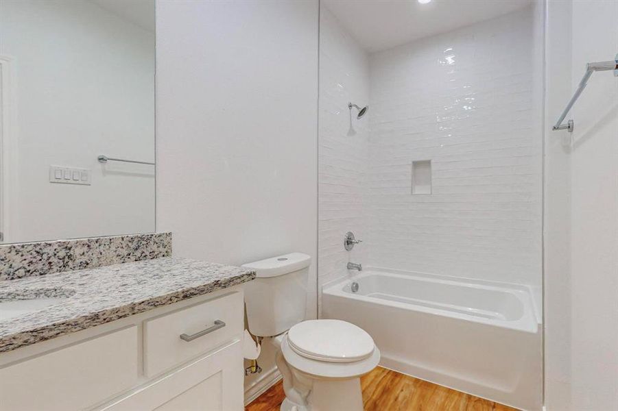 Full hall bathroom with washtub / shower combination, vanity, wood-type flooring, and toilet