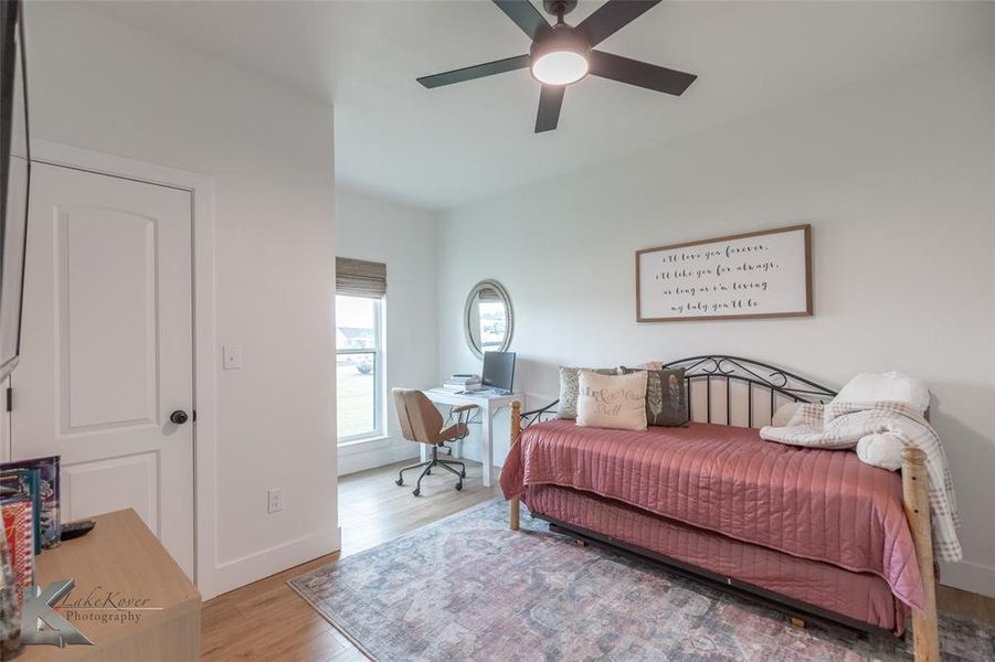 Bedroom with an office area, wood finished floors, and ceiling fan Bedroom with an office area, wood finished floors, and ceiling fan