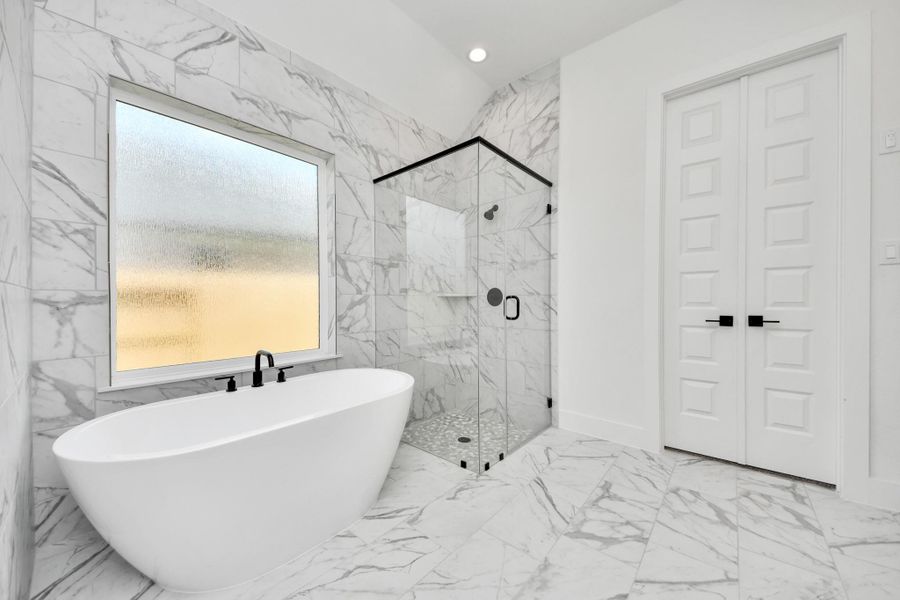 Escape to a spa-like oasis in this primary bathroom. Enjoy a walk-in shower with tile surround, a separate garden tub with custom detailing, and an elegant vanity featuring light countertops, modern hardware, and beautiful recessed lights. Experience luxury and relaxation in every detail. Escape to a spa-like oasis in this primary bathroom. Enjoy a walk-in shower with tile surround, a separate garden tub with custom detailing, and an elegant vanity featuring light countertops, modern hardware, and beautiful recessed lights. Experience luxury and relaxation in every detail.