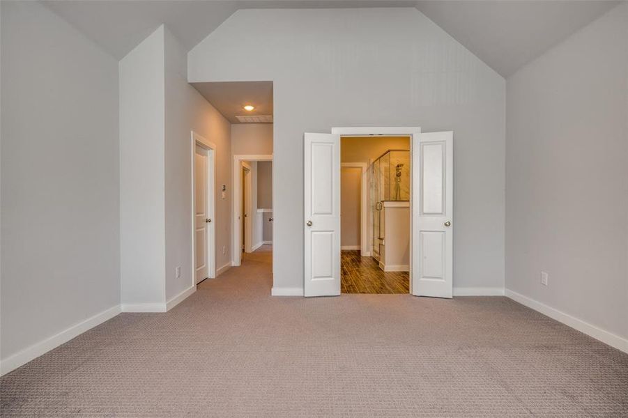 Unfurnished bedroom with carpet flooring, baseboards, and high vaulted ceiling