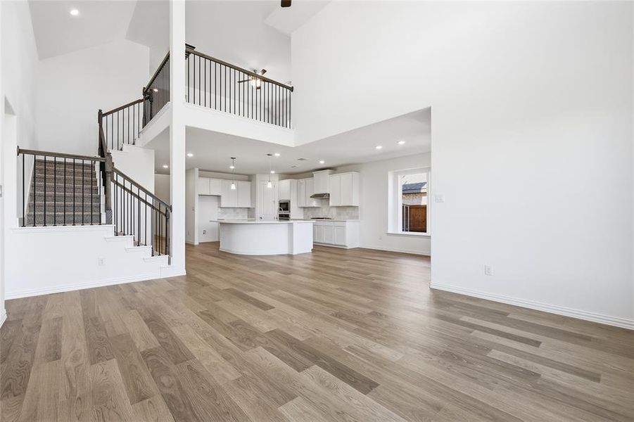 Unfurnished living room featuring recessed lighting, light wood-type flooring, and a high ceiling