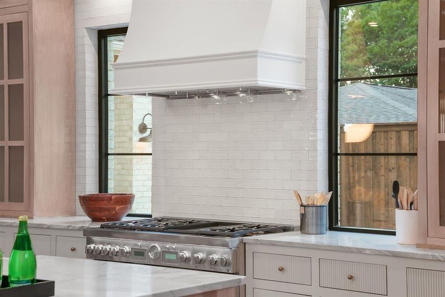 The kitchen features a professional-grade stainless steel range, a complementary white range hood, and white subway tile backsplash
