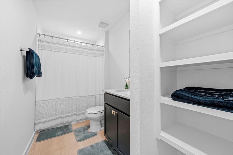 This stylish bathroom showcases a rich dark vanity accented by contrasting hardware, paired with a light countertop and thoughtfully integrated shelving for a refined, organized feel. This stylish bathroom showcases a rich dark vanity accented by contrasting hardware, paired with a light countertop and thoughtfully integrated shelving for a refined, organized feel.