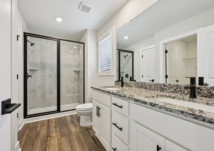 The master bathroom features dual vanity sinks and a glass-enclosed shower.