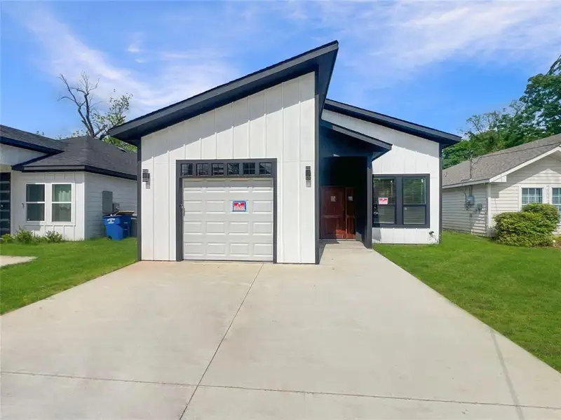 View of front of property featuring board and batten siding, an attached garage, a front lawn, and concrete driveway View of front of property featuring board and batten siding, an attached garage, a front lawn, and concrete driveway