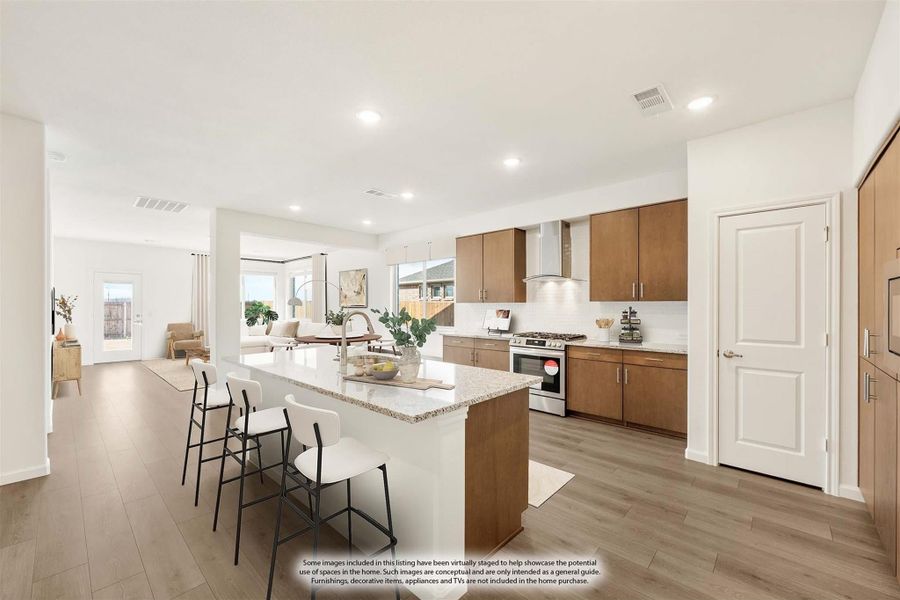 Open kitchen with large island, granite countertops, wood cabinets, and stainless steel appliances, open to living area