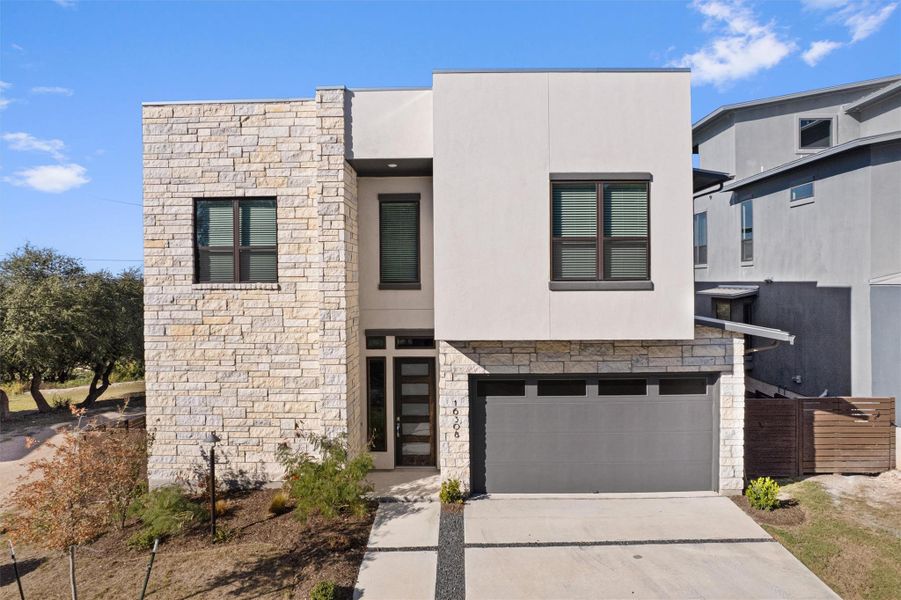 Contemporary home with stone siding, stucco siding, driveway, and an attached garage Contemporary home with stone siding, stucco siding, driveway, and an attached garage