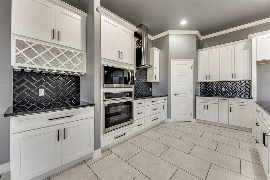 Kitchen featuring decorative backsplash, appliances with stainless steel finishes, crown molding, and wall chimney exhaust hood