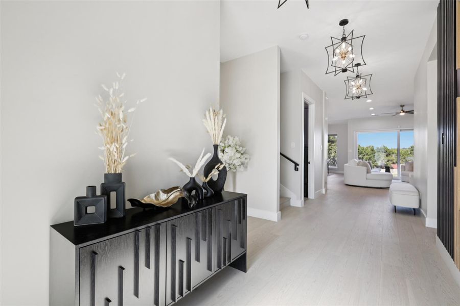 Hall featuring light wood finished floors and hanging lights