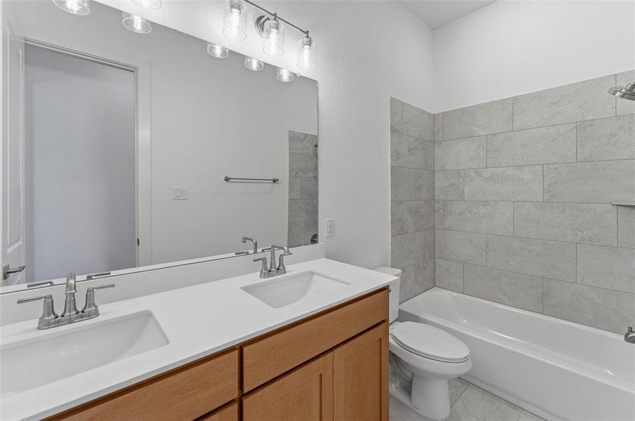 Bathroom featuring a double vanity with light wood-finish cabinetry, white countertop, and integrated sinks