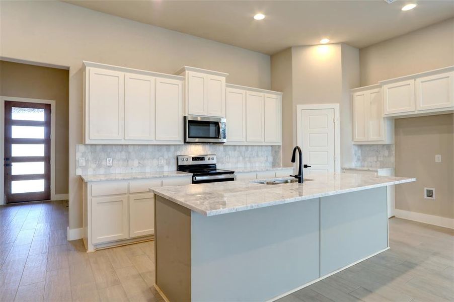 Kitchen featuring stainless steel appliances, an island with sink, and sink