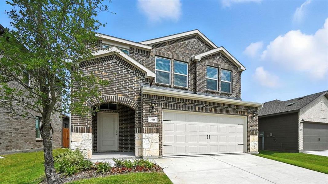 View of front of property featuring brick siding, driveway, a garage, stone siding, and a front yard View of front of property featuring brick siding, driveway, a garage, stone siding, and a front yard