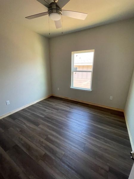 Empty room with ceiling fan and dark wood-type flooring