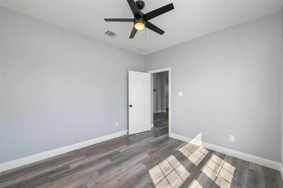 Empty room with wood finished floors and a ceiling fan Empty room with wood finished floors and a ceiling fan