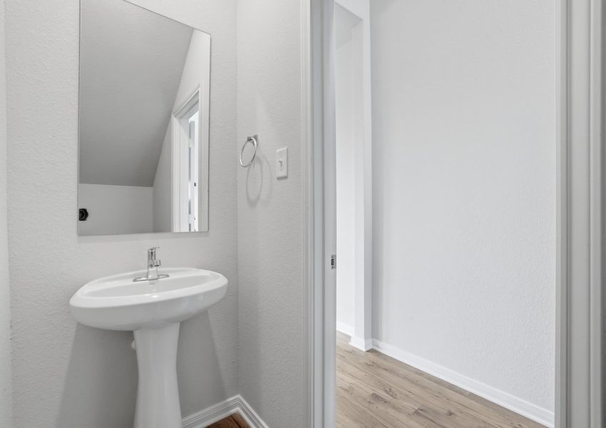 First-floor powder room featuring a pedestal sink and wood-look vinyl flooring.