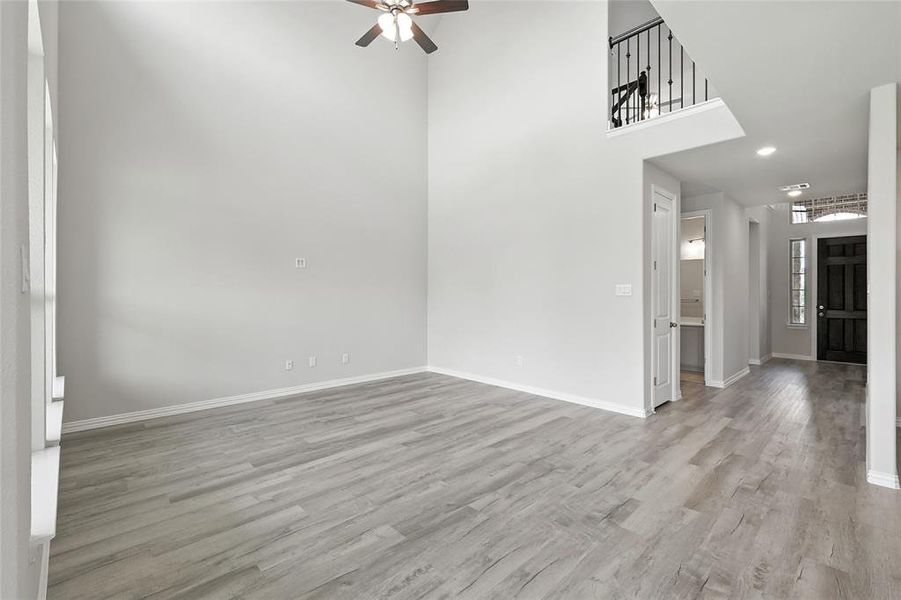 Empty room with a ceiling fan, wood finished floors, recessed lighting, and a towering ceiling Empty room with a ceiling fan, wood finished floors, recessed lighting, and a towering ceiling