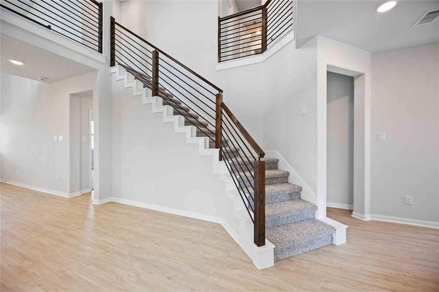 This home showcases a modern interior featuring a stylish staircase with sleek dark wood railings and horizontal metal balusters. The stairs are carpeted, adding a warm and comfortable touch to the space.