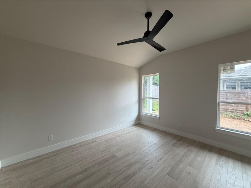 A quiet bedroom retreat with vaulted ceilings and wood flooring, ready for personalization.