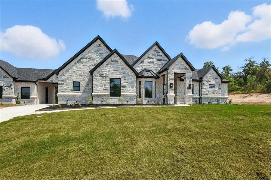 French provincial home featuring a front lawn and stone siding